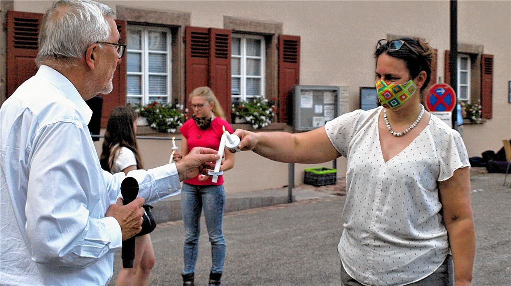 Christine von Wagner, Pfarrerin der evangelischen Verbundkirchengemeinde Maulbronn-Umland, reicht die Flamme ihrer Friedenskerze weiter an Hansjörg Lechler, den früheren Pfarrer von Zaisersweiher-Schmie. Foto: Filitz