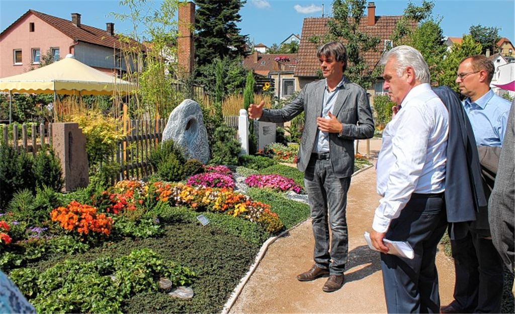 Christof Hilligardt (li.) führt Heribert Rech und OB Schneider (re.) durch den Garten.