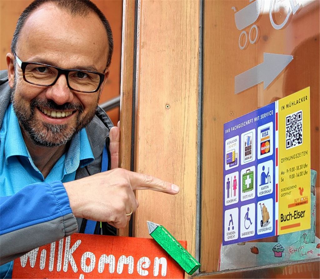 Citymanager Thomas Müller präsentiert die neuen Schilder, die an verschiedenen Geschäften in der ganzen Stadt angebracht sind – hier bei Buch-Elser an der Bahnhofstraße.
