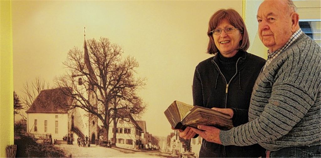 Cornelia Schuler und Werner Augenstein mit einer französischen Bibel der Familie Walter Roux aus dem Jahr 1811. Im Hintergrund Pinache im Jahr 1899 mit der Hauptstraße.