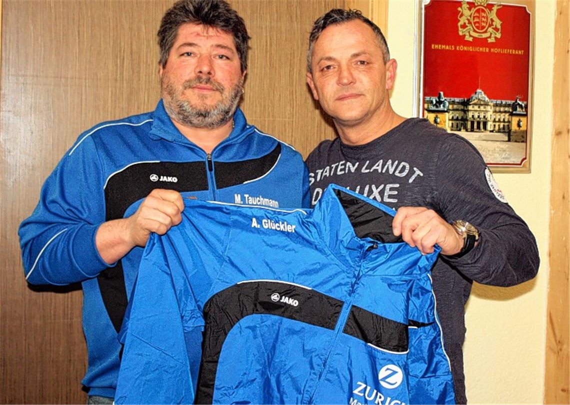 Damit er bei seinen ersten Auftritten als neuer Trainer nicht im Regen stehen muss, bekommt Achim Glückler (re.) vom Ötisheimer Fußballabteilungsleiter Michael Tauchmann eine Regenjacke überreicht. 