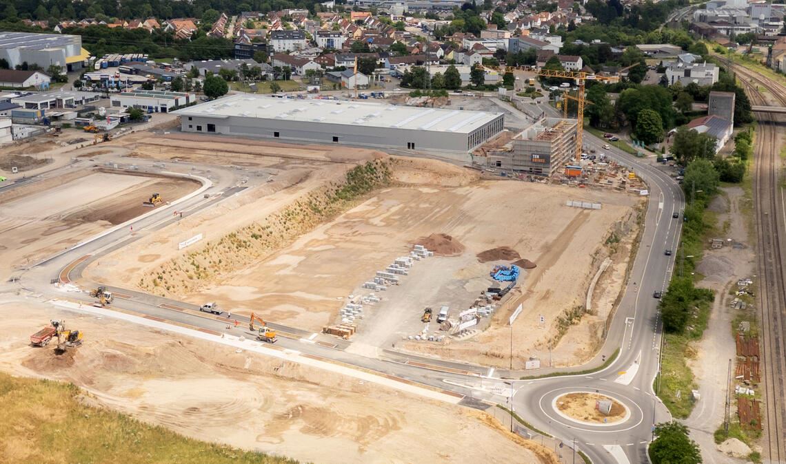 Das Grundstück für die neuen Lebensmittelmärkte – an der Ziegeleistraße zwischen der neuen Erschließungsstraße mit Kreisverkehr (unten) und dem neuen Baumarkt, der im Hintergrund entsteht, gelegen – ist vorbereitet. Doch nach dem Ausstieg des alten Investors feilen die künftigen Nachbarn Aldi und Edeka noch an ihren Planungen. Foto: Fotomoment