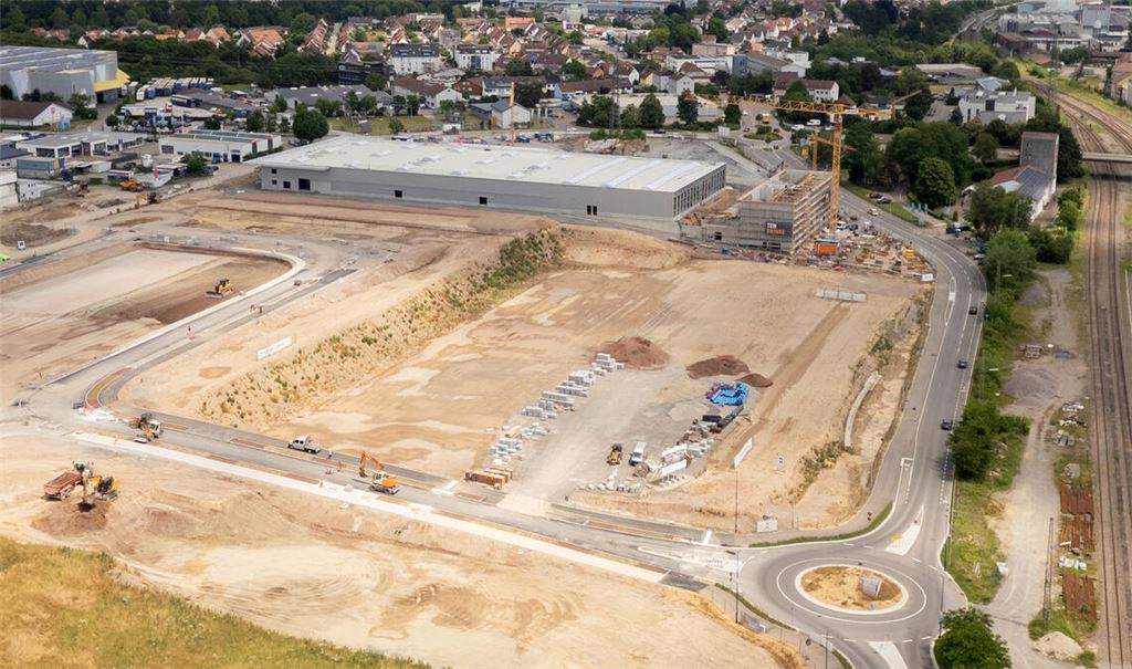 Das Grundstück für die neuen Lebensmittelmärkte – an der Ziegeleistraße zwischen der neuen Erschließungsstraße mit Kreisverkehr (unten) und dem neuen Baumarkt, der im Hintergrund entsteht, gelegen – ist vorbereitet. Doch nach dem Ausstieg des alten Investors feilen die künftigen Nachbarn Aldi und Edeka noch an ihren Planungen. Foto: Fotomoment