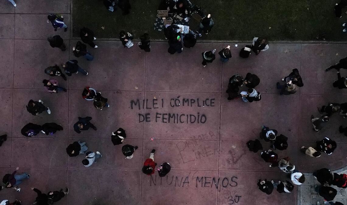 Demonstranten gehen in Buenos Aires in der Nähe eines Schriftzugs "Milei femicide accomplice" (Milei Frauenmord Mittäter), der sich auf Präsident Javier Milei bezieht, während eines Marsches zum Jahrestag der Frauenbewegung "Ni Una Menos" (Nicht eine weniger).