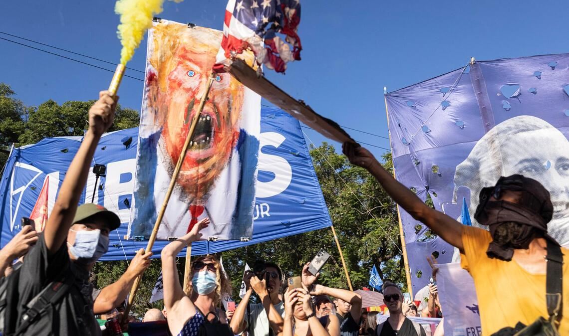 Demonstranten zünden mit einer Fackel eine amerikanische Fahne an.