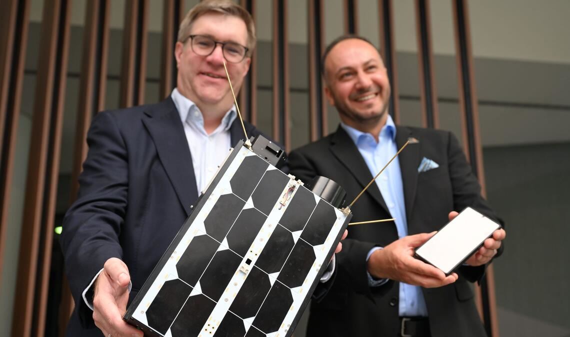 Demonstrativ gute Laune von O2-Manager Jörg Kablitz und OQ-Chef Omar Qaise, die bei der Vorstellung ihres Vorhabens ein Modell eines Satelliten dabeihatten.