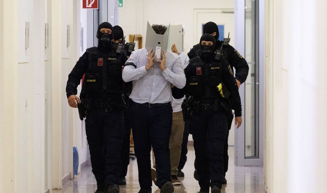 Der Angeklagte im Prozess um mutmaßliche Anschlagspläne auf das Wiener Taylor-Swift-Konzert wird von Polizei im Gericht begleitet.