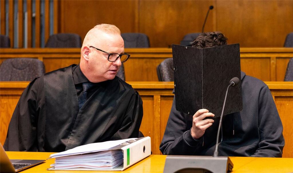 Der Angeklagte sitzt neben seinem Verteidiger im Gerichtssaal.