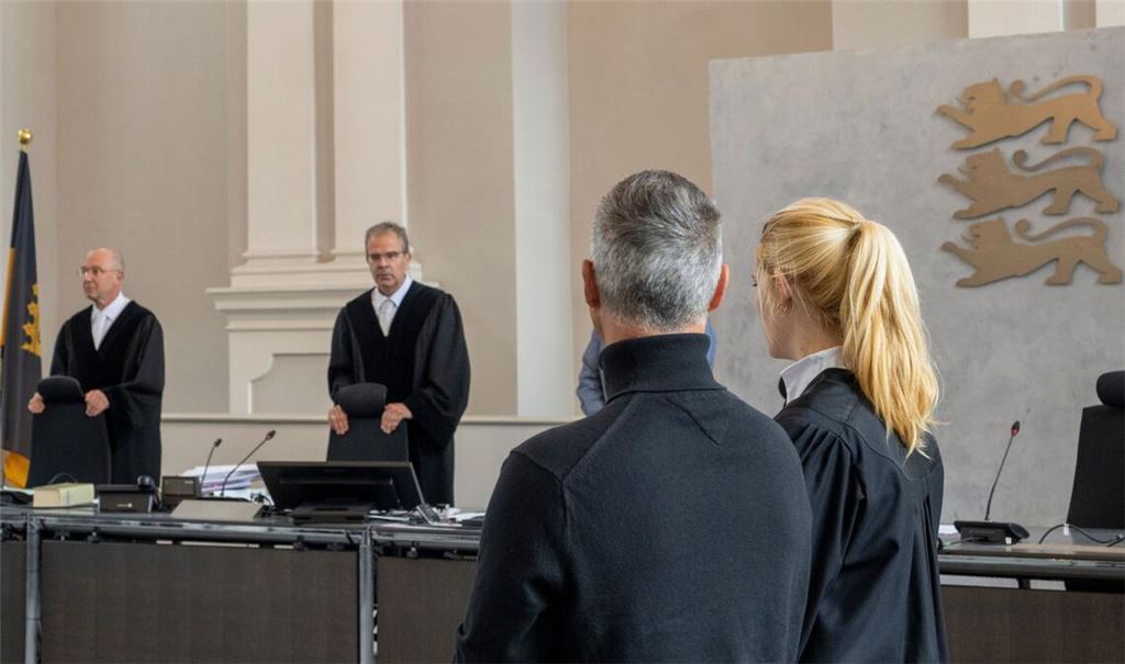 Der Angeklagte steht im Landgericht neben seiner Verteidigerin Charlotte Warken-Luxenburger.