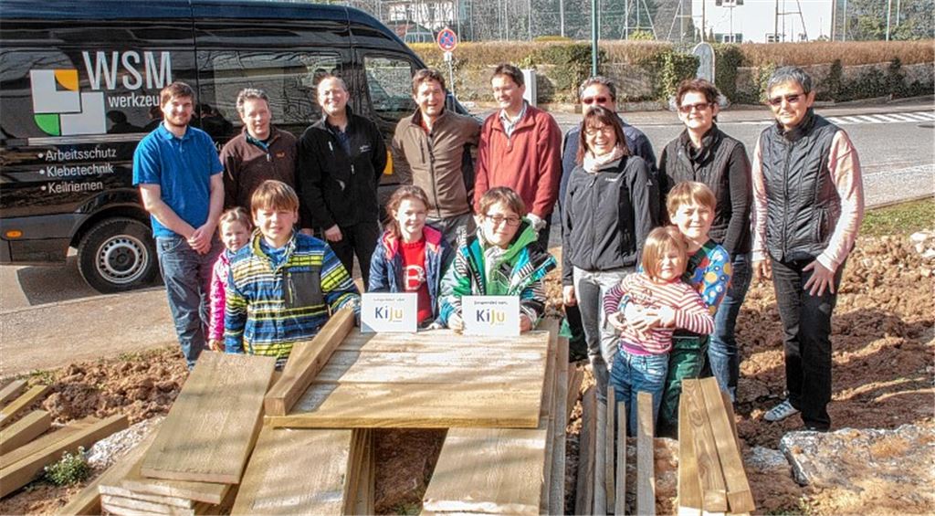 Der Arbeitstrupp von KiJU, Vertreterinnen von Schulleitung und Elternbeirat und einige junge Helfer packen gemeinsam für den Bau von zwei Hochbeeten für die Schillerschule an.