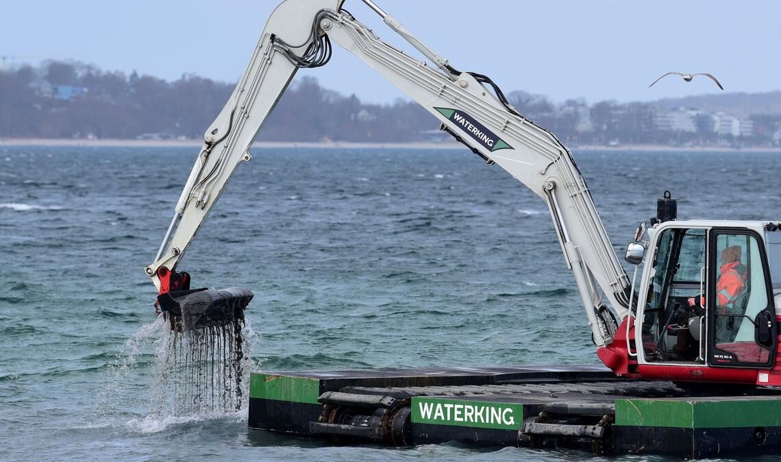 Der Bagger gräbt eine Rinne für den gestrandeten Wal.