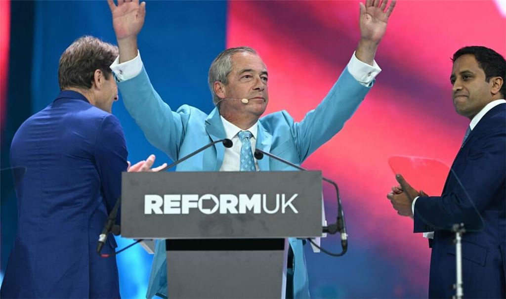 Der Chef der Reform UK Partei, Nigel Farage, wird nach seiner Rede auf dem Parteitag in Birmingham gefeiert. Auf der Bühne spenden ihm der stellvertretende Vorsitzende Richard Tice (L) und der Schatten-Innenminister Zia Yusuf Beifall.
