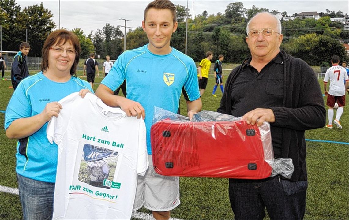 Der Ehrenamtsbeauftragte des Württembergischen Fußballverbands, Heinz Krauss (re.), überreicht Felix Weber als Anerkennung seines vorbildlichen Verhaltens ein T-Shirt und eine Sporttasche. Über die Ehrung freut sich Annemarie Gutscher, Jugendleiterin bei Phönix. 