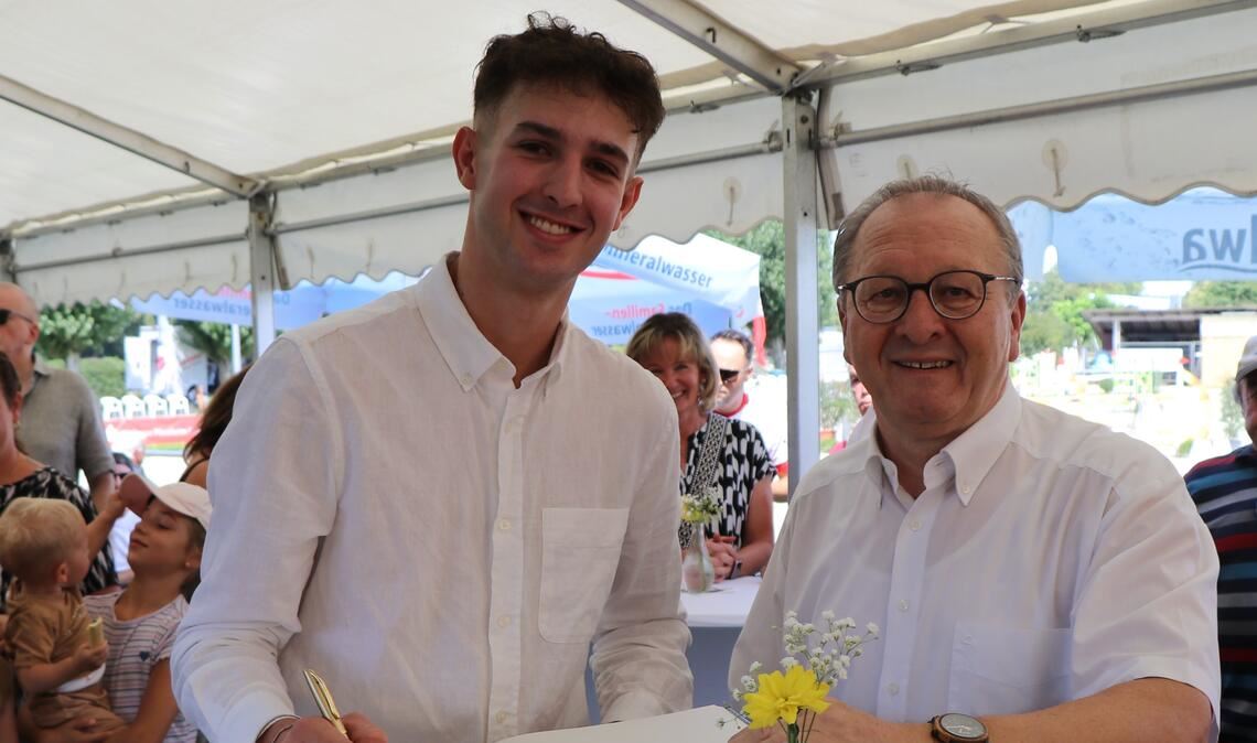 Der Europameister Moritz Treffinger (li., mit Bürgermeister Thomas Nowitzki) trägt sich ins Goldene Buch ein. Foto: Behice Demir