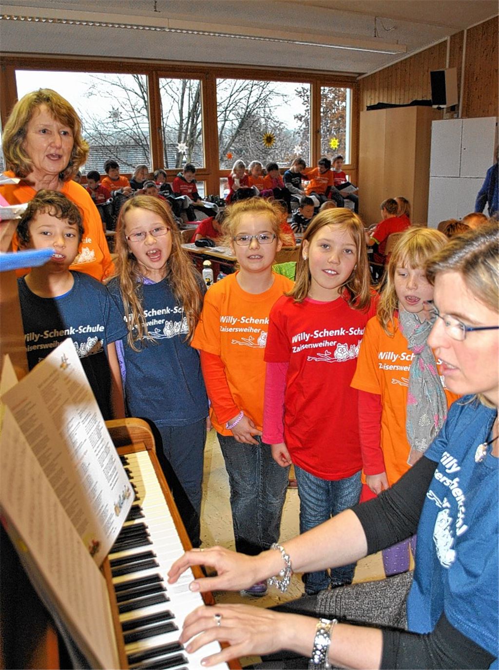 Der Grundschulchor, hier mit Leiterin Monika Bendlin am Klavier und Schulleiterin Andrea Bernhard, wird auch dieses Jahr bei den Chortagen „Kinder helfen Kindern“ dabei sein. 