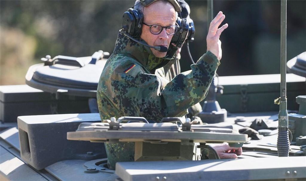 Der Kanzler grüßt aus einem gepanzerten Fahrzeug beim Truppenbesuch in Munster.