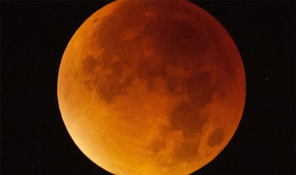 Der Mond erscheint am 21. Januar über Stuttgart während einer Mondfinsternis fast vollständig in einem rötlichen Farbton. Ursache des roten Schimmers sind die roten Anteile des Spektrums der Sonnenstrahlen, die durch die Erdatmosphäre in den Kernschatten der Erde abgelenkt werden.