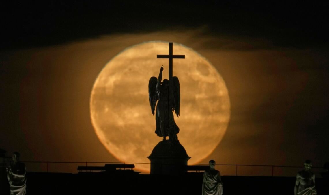 Der Mond geht hinter einer Engelsstatue auf der Alexandersäule auf dem Palastplatz über St. Petersburg auf.