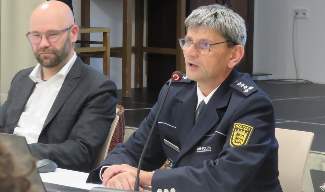 Der Mühlacker Revierleiter Achim Strobel (re.) hat neben Bürgermeister Alexander Kozel Platz genommen und stellt Verwaltung, Gemeinderat und den Zuhörerinnen und Zuhörern die Kriminalitäts- und Unfallstatistik für 2023 vor. Foto: Becker