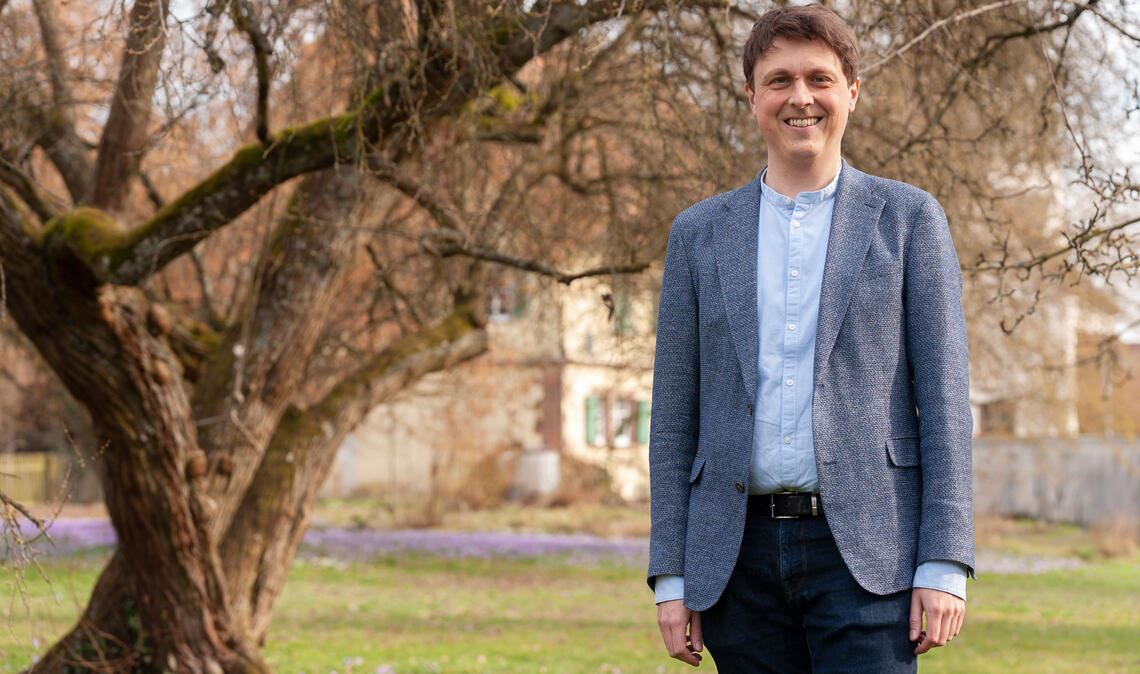 Der Pfarrgarten in Zaisersweiher beschert Dr. Lukas Lorbeer zum Abschied ein prachtvolles Krokusmeer, das im Hintergrund aufleuchtet. Foto: Fotomoment