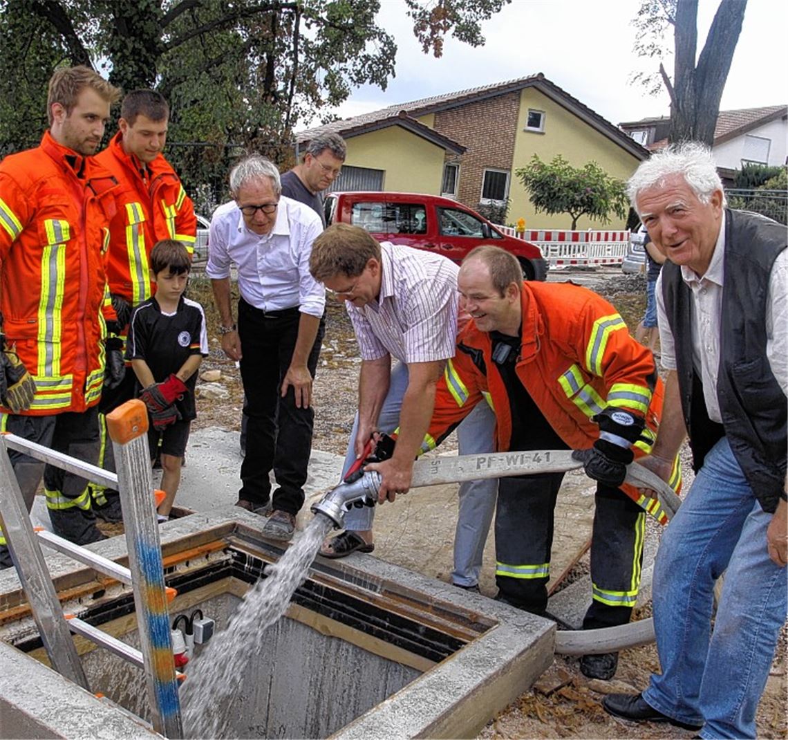 Der Schultes (Mitte) packt mit an: Der 100 Kubikmeter große Erdspeicher wird mit Wasser befüllt.