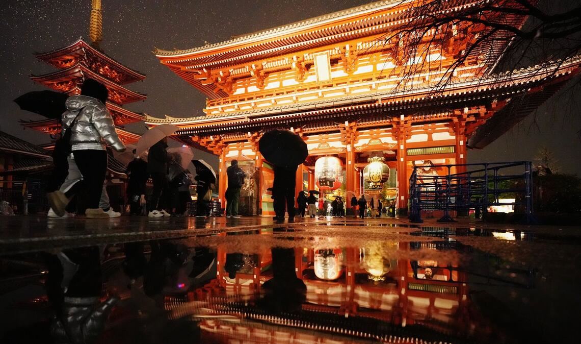 Der Sensoji-Tempel spiegelt sich in einer Pfütze, als Menschen zum Neujahrsgebet in Tokio ankommen.