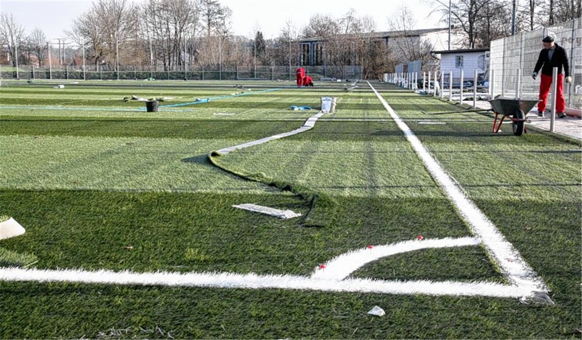 Der Spielbelag ist verlegt, die Linien sind gezogen, derzeit wird ein Granulat zwischen die künstlichen Grashalme eingearbeitet, das dem Platz annähernd natürliche Eigenschaften verleiht. Foto: Goertz