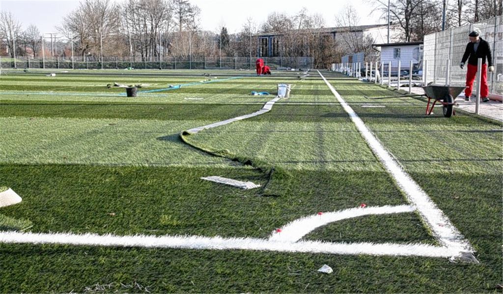 Der Spielbelag ist verlegt, die Linien sind gezogen, derzeit wird ein Granulat zwischen die künstlichen Grashalme eingearbeitet, das dem Platz annähernd natürliche Eigenschaften verleiht. Foto: Goertz