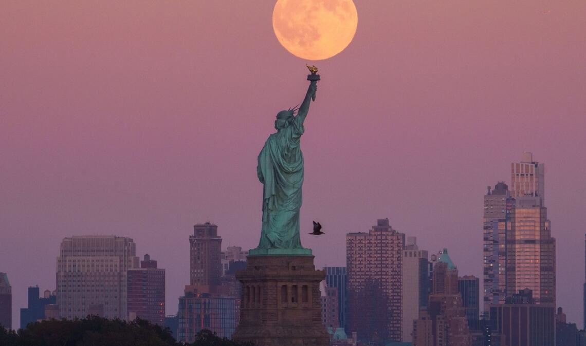 Der Supermond geht hinter der Freiheitsstatue in New York auf.