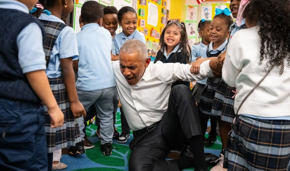 Der frühere US-Präsident Barack Obama lässt sich beim Aufstehen von Kindern hochheben.