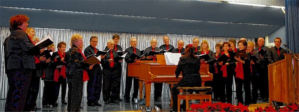 Der gemischte Chor mit Dirigentin Esther Rau am Klavier und Aaron Combe (rechts am Pult) als Erzähler im Stück „Hört die Weihnachtsgeschichte“.