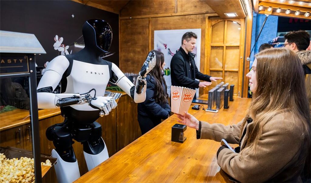 Der humanoide Roboter "Optimus" von Tesla verteilt bei seiner Vorstellung in der Mall of Berlin Popcorn an eine Besucherin.