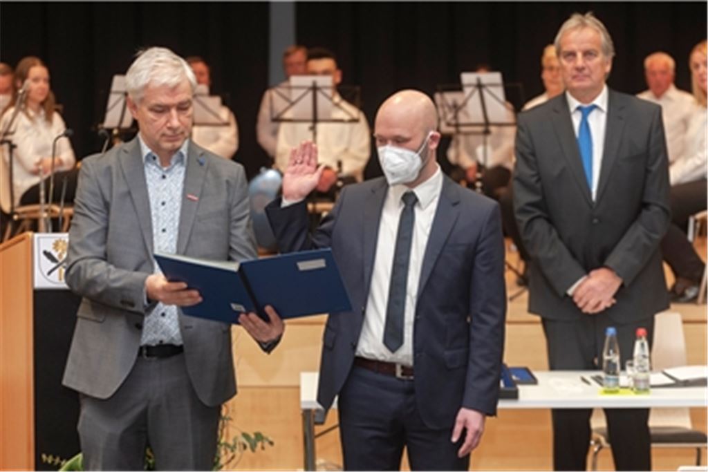 Der neue Knittlinger Bürgermeister Alexander Kozel legt den Amtseid ab. Die Verpflichtung nimmt der Stadtrat und Erste Bürgermeisterstellvertreter Martin Reinhardt (li.) vor. Der Gemeinderat hat ihn zuvor per einstimmigem Beschluss mit dieser Aufgabe betraut. Schultes-Vorgänger Heinz-Peter Hopp verfolgt die Szene. Im Hintergrund sind Mitglieder der Stadtkapelle Knittlingen zu sehen. Das Ensemble umrahmt die unter Corona-Bedingungen stattfindende Veranstaltung mit flotter Marsch- und Unterhaltungsmusik. Fotos: Fotomoment