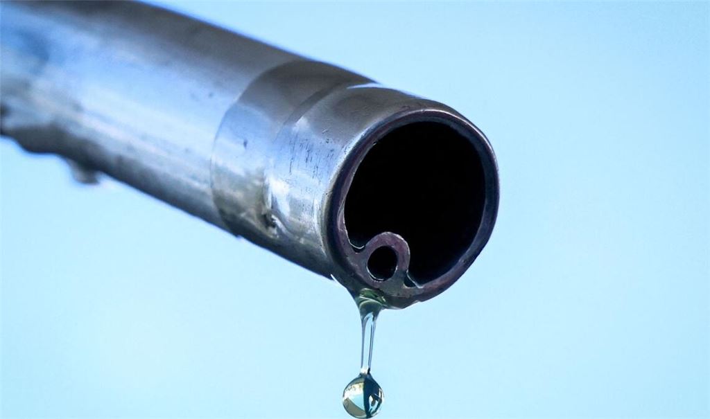 Der soll doch in den Tank! Ein Tropfen Benzin an einer Zapfsäule auf dem Weg nach unten.