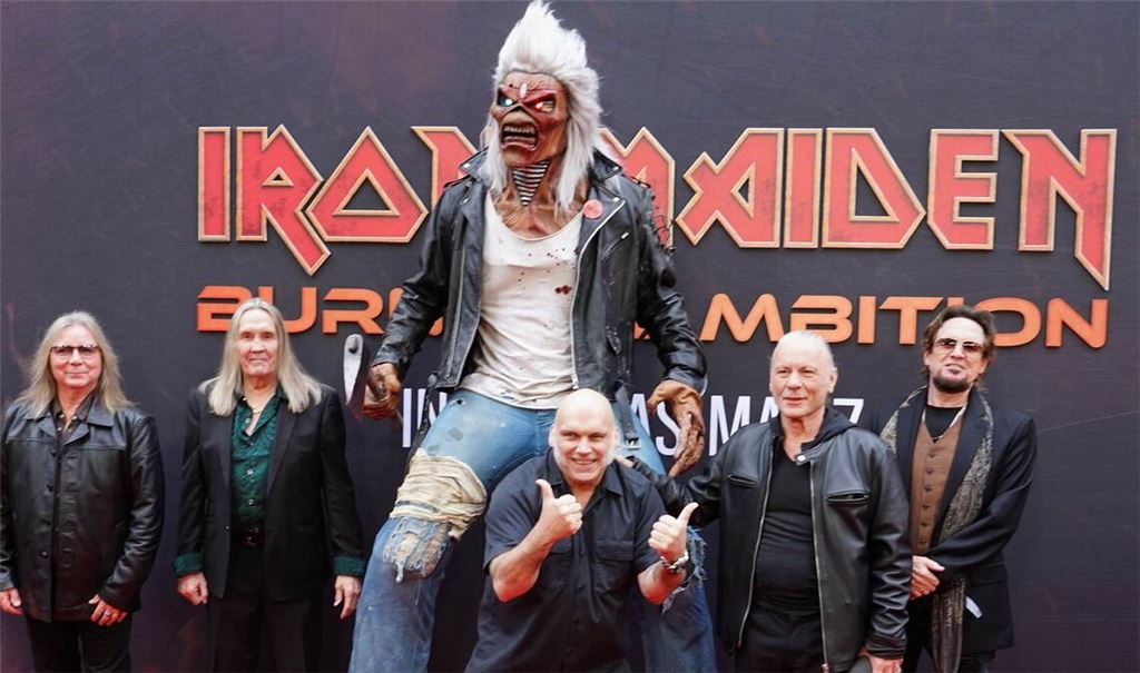 Die Bandmitglieder von Iron Maiden bei der Weltpremiere des Dokumentarfilms „Burining Ambition“ – Maskottchen Eddie darf natürlich nicht fehlen.