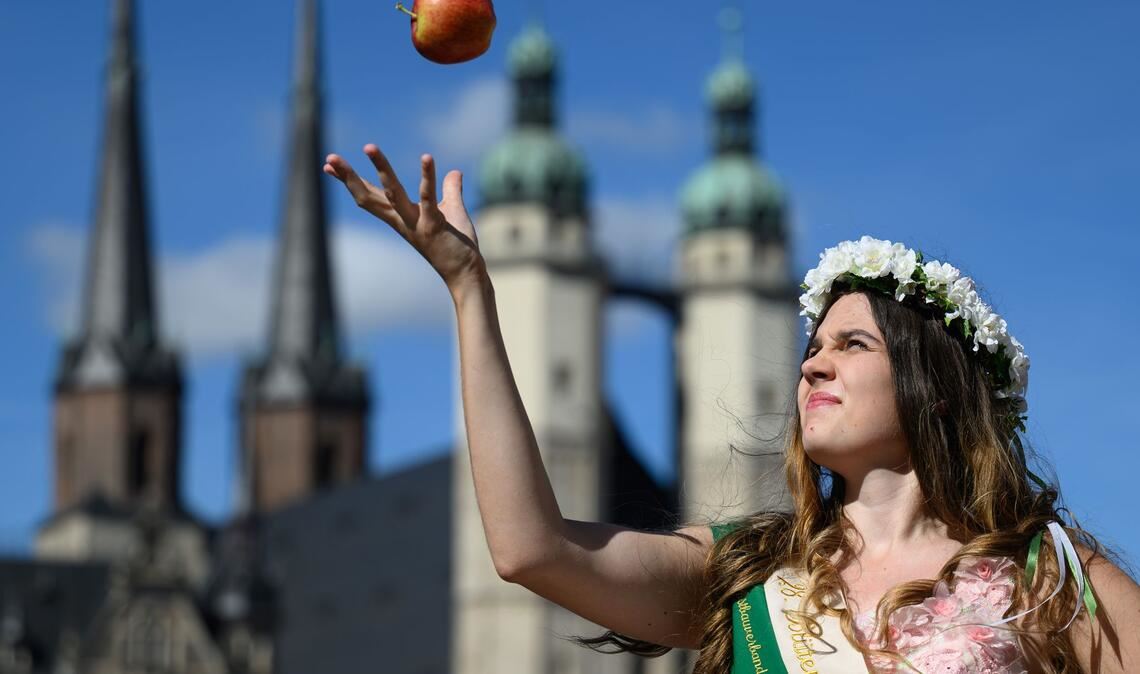 Die Blütenkönigin Alida I. jongliert mit einem Apfel zu Eröffnung der Apfelsaison in Halle (Saale).