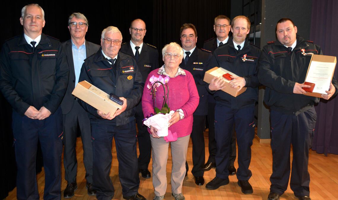 Die Ehrungen mit Kommandant Martin Beller (v.l.) Bürgermeister Armin Pioch, dem Geehrten Willi Weischedel, Kreisbrandmeister Carsten Sorg, Ruth Weischedel, dem stellvertretenden Kreisbrandmeister Florian Becker, dem stellvertretenden Feuerwehrverbands-Vorsitzenden Michael Gutjahr sowie den Geehrten Oliver Marzian und Tobias Bühler.
