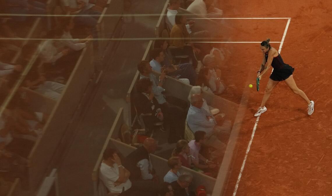 Die Fans spiegeln sich in einer Glaswand bei den French Open, während Aryna Sabalenka eine Rückhand gegen Naomi Osaka spielt.