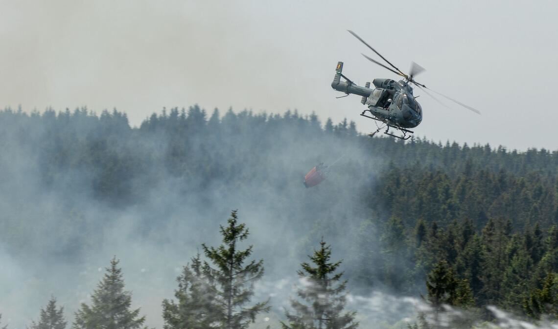 Die Feuerwehr versucht mit einem Hubschrauber einen Moorbrand im deutsch-belgischen Grenzgebiet bei Aachen zu löschen.