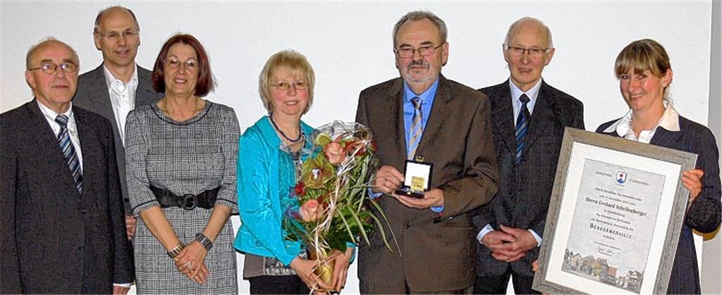 Die Gemeinde bedankt sich mit der Bürgermedaille in Gold: Bürgermeister a. D. Helmut Wagner, die beiden Fraktionschefs Rolf Fazler (Freie Wähler) und Marie-Luise Rohde (SPD, v. li.) sowie Bürgermeisterin Sigrid Hornauer und Bürgermeister a. D. Horst Jung (v. re.) würdigen das Engagement von Gerhard Schollenberger. Ann-Christin Schollenberger nimmt als Dankeschön einen Blumenstrauß entgegen.