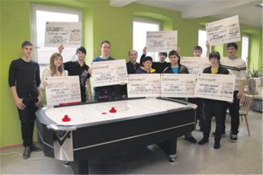 Die Illinger Jugendhausbesucher halten die Schecks der Firmen in die Höhe, mit deren Unterstützung unter anderem der Airhockeytisch angeschafft werden konnte. Über die Spenden freuen sich auch Interimsbetreuer Daniel Claß (li.) und Bürgermeister Harald Eiberger (5.v.li.). 
Foto: Disselhoff