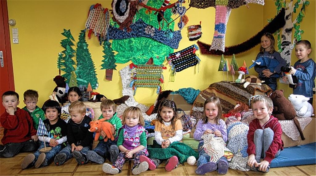 Die Kindergartenkinder präsentieren Material, mit dem die Kirche eingepackt wird.