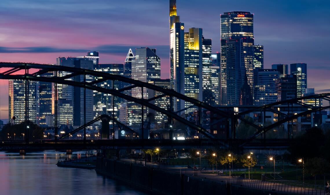 Die Lichter der Bankenskyline von Frankfurt leuchten in der Abendstimmung.