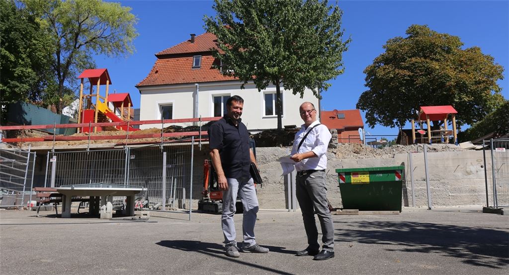 Die Mauer zwischen Kindergarten und Schulhof in Dürrmenz muss noch saniert werden, erklären Joachim Dick (li.) und Bürgermeister Winfried Abicht, aber dafür stehen die neuen Spielgeräte für die Rückkehrer bereit. Nach über einem halben Jahr in den Räumlichkeiten der UvD-Schule dürfen die Schulstraßen-Kindergartenkinder zurück ins Domizil.Fotos: Deeg