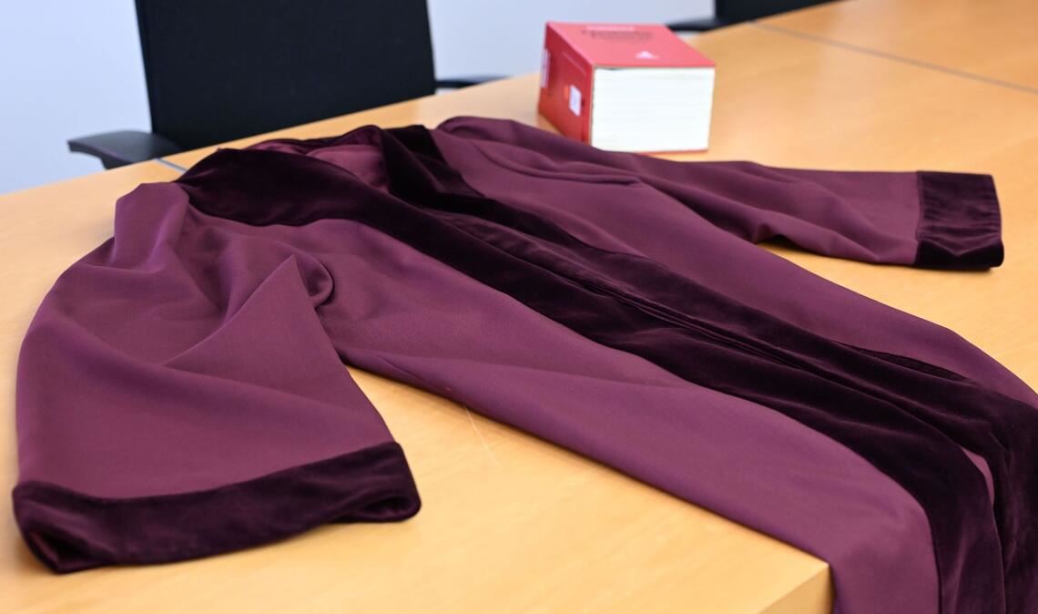 Die Robe zeichnet sich durch den tiefen Rot-Ton und den Samtbesatz an Ärmeln und Kragen aus.