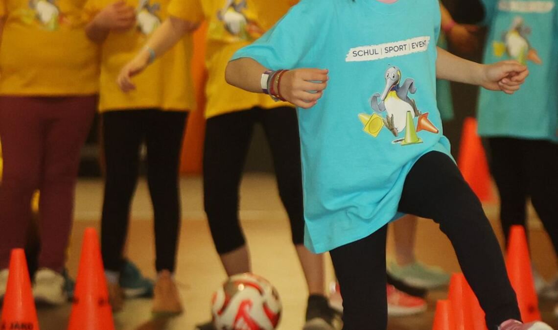 Die Schlangen-Station: mit einem Fußball dribbeln die Kinder im Slalom durch die Hütchen.