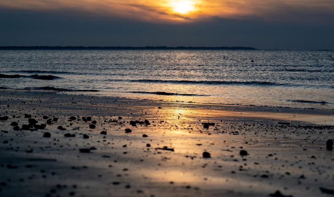Die Sonne geht am Strand der Insel Langeoog über der Nordsee unter.
