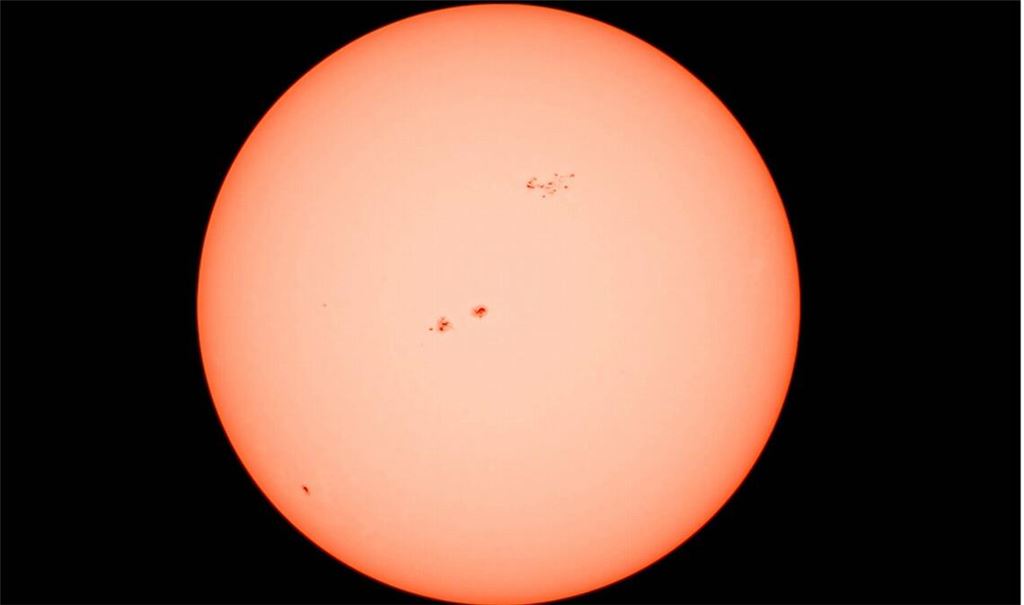 Die Sonne in all ihrer Kraft aufgenommen durch ein Teleskop mit Sonnenfilter. Deutlich sichtbar: mehrere Sonnenflecken auf der glühenden Oberfläche, die eindrucksvoll die Dynamik und Aktivität unseres Sterns zeigen.