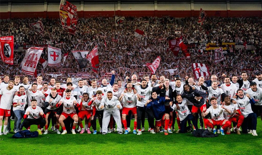 Die Spieler des SC Freiburg jubeln nach dem Einzug ins Europa League Finale bei einem Gruppenbild mit den Fans.