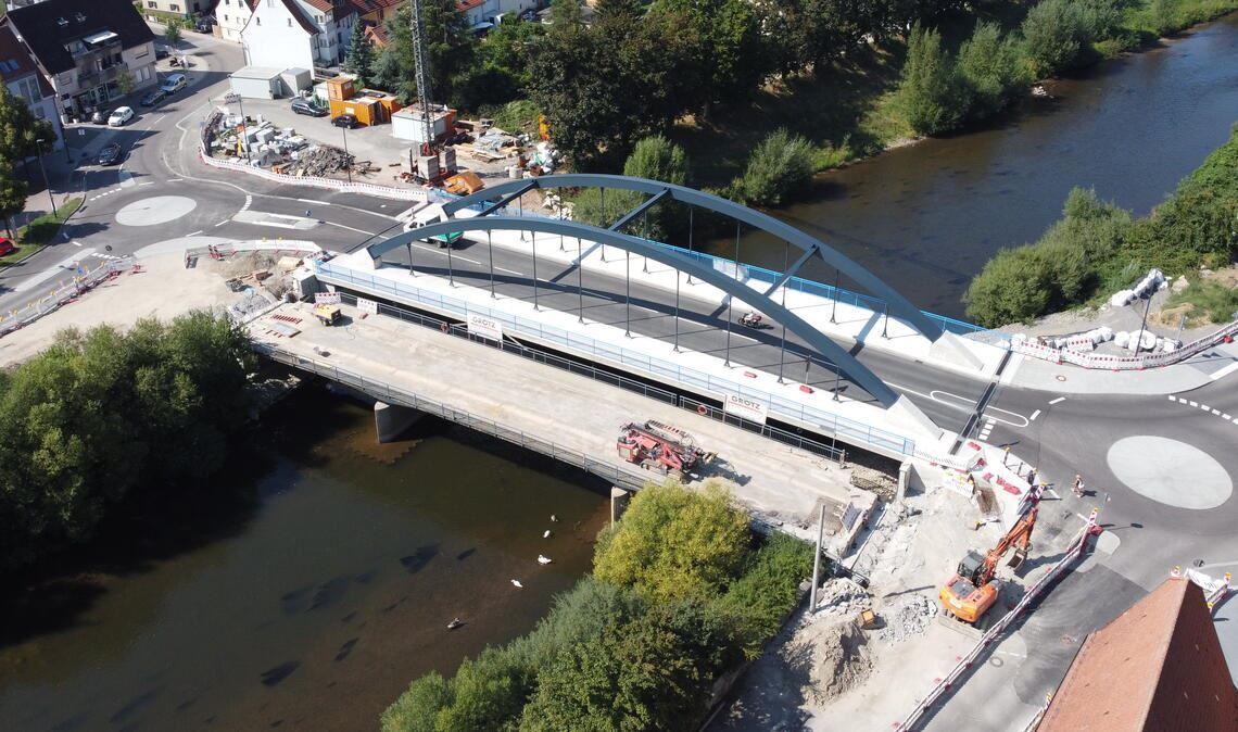 Die unterhalb des neuen Bauwerks liegende alte Brücke wird für den Abbruch in zwölf Teile zersägt, die vom Mobilkran ans Ufer gehievt und dort zerkleinert werden. Foto: Schramm